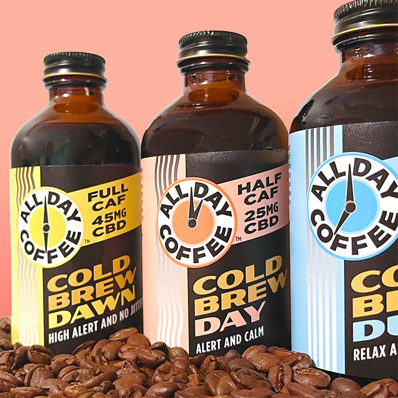 All Day Coffee bottles in a row on a bed of coffee beans